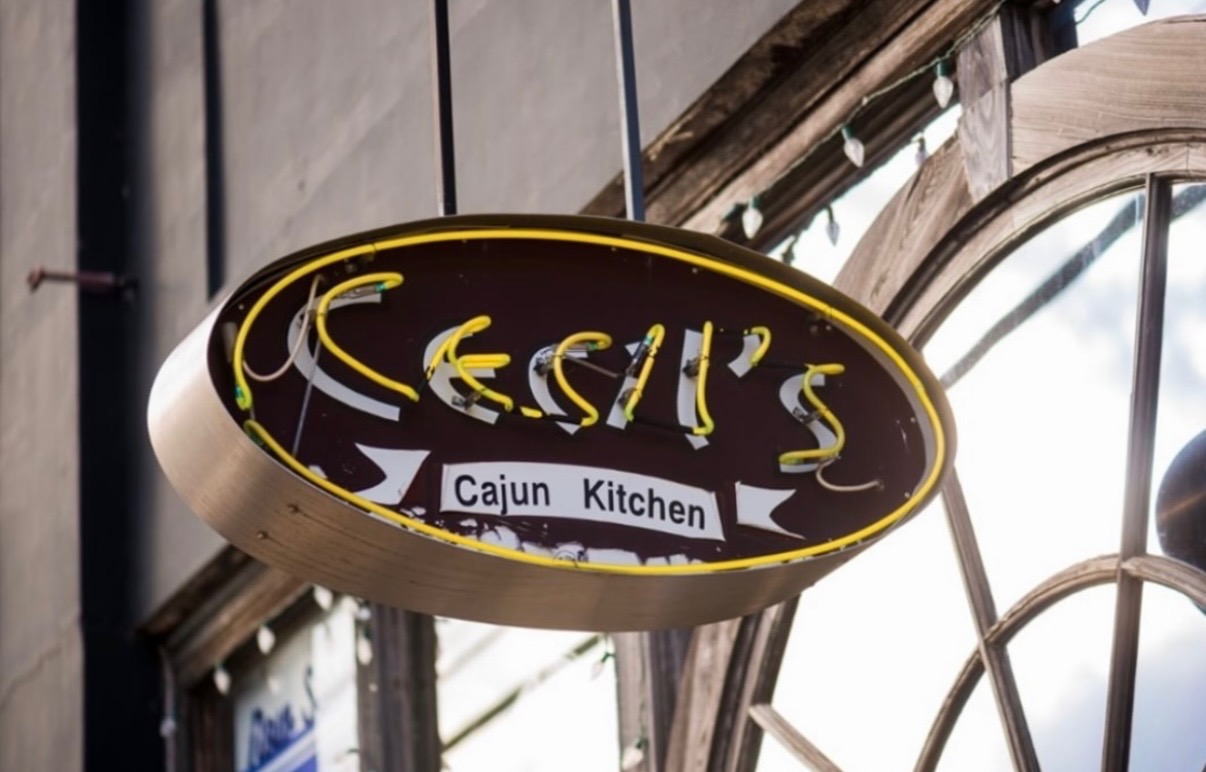 The yellow neon Cecil's Cajun Kitchen sign hanging outside